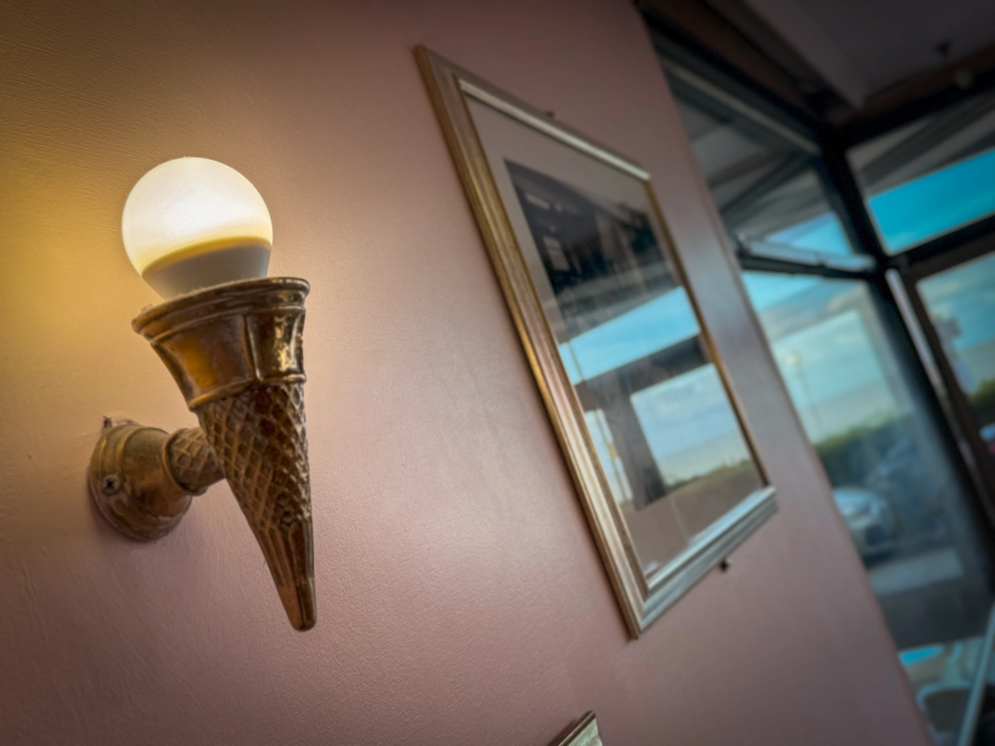 An ice cream cone wall sconce glowing on the parlour wall