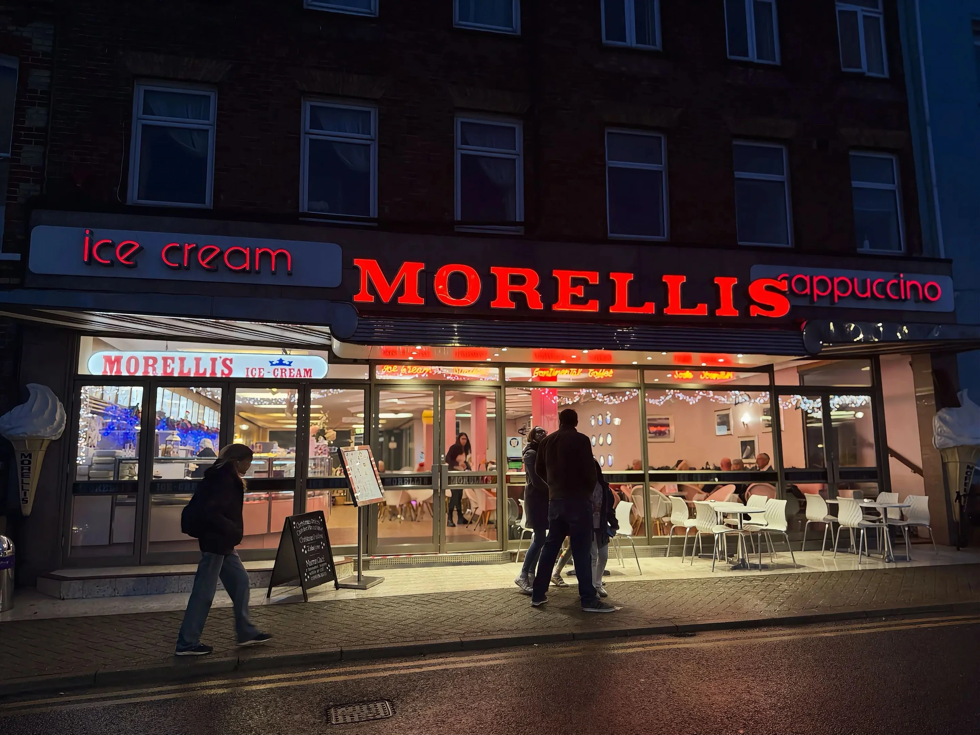 The Morelli's neon sign glowing over the promenade at night